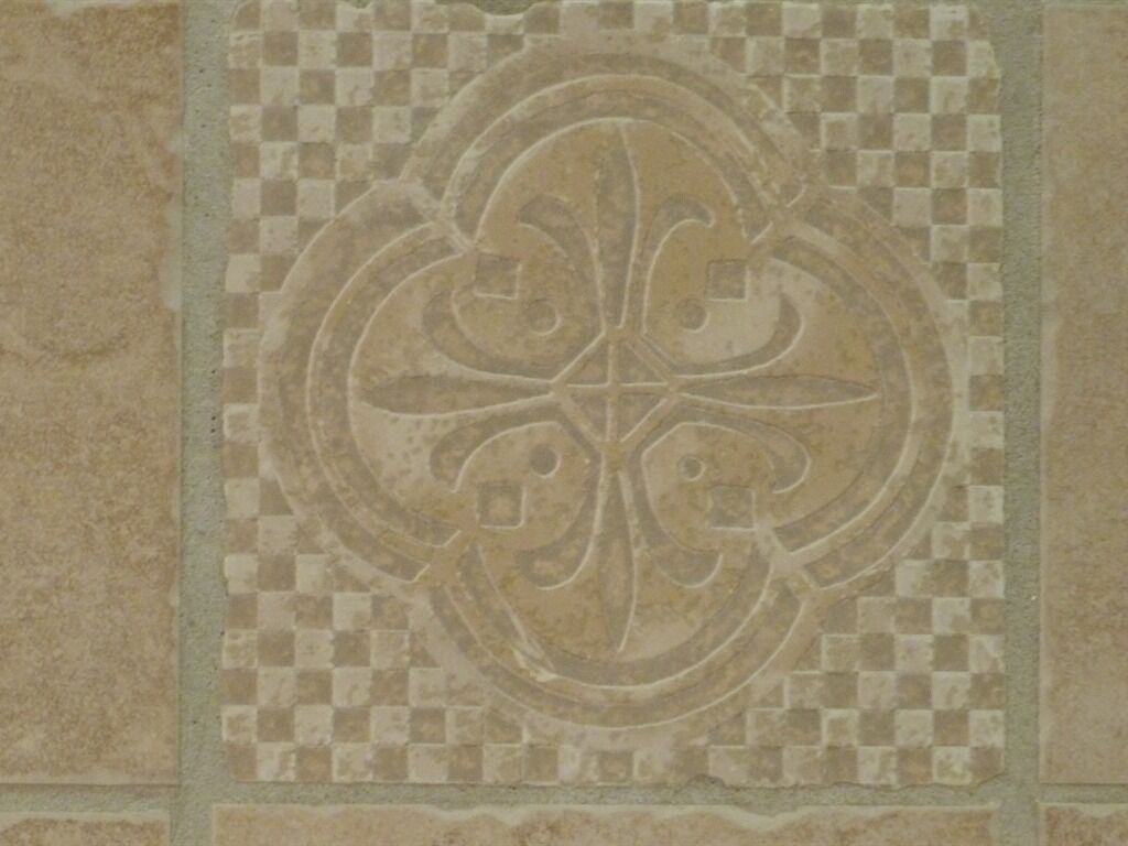A tile with a decorative fleur-de-lis pattern.