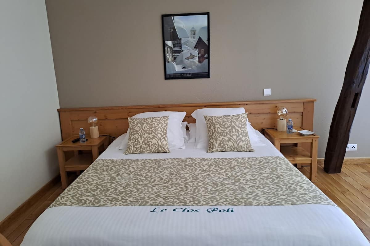 Ein Hotelzimmer mit einem großen Bett, zwei Nachttischen, einem gerahmten Bild an der Wand und Holzboden.