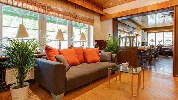 A cozy seating area with a sofa, a glass coffee table, and potted plants. - Hotel Garni Fock Und Oben (Hamburg)