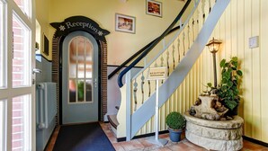 A reception area with a staircase, a door with a sign, and a potted plant. - Hotel Garni Fock Und Oben (Hamburg)