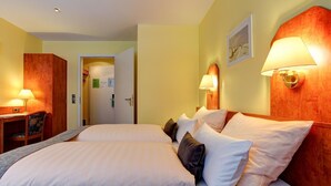 A hotel room with a double bed, two bedside tables with lamps, a desk with a chair, and a door leading to another room. - Hotel Garni Fock Und Oben (Hamburg)