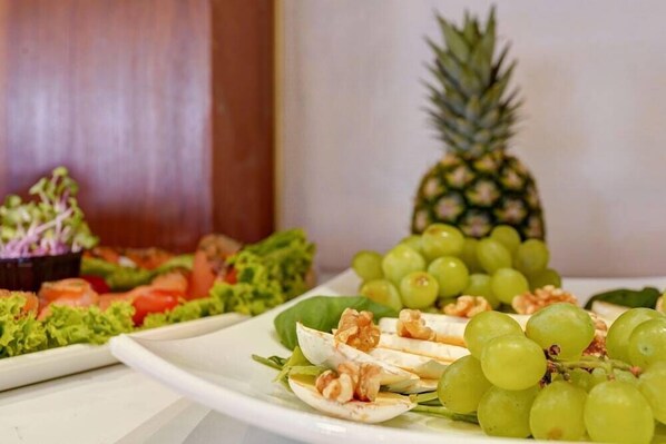 A variety of food items including grapes, walnuts, and a pineapple on a plate. - Hotel Garni Fock Und Oben (Hamburg)
