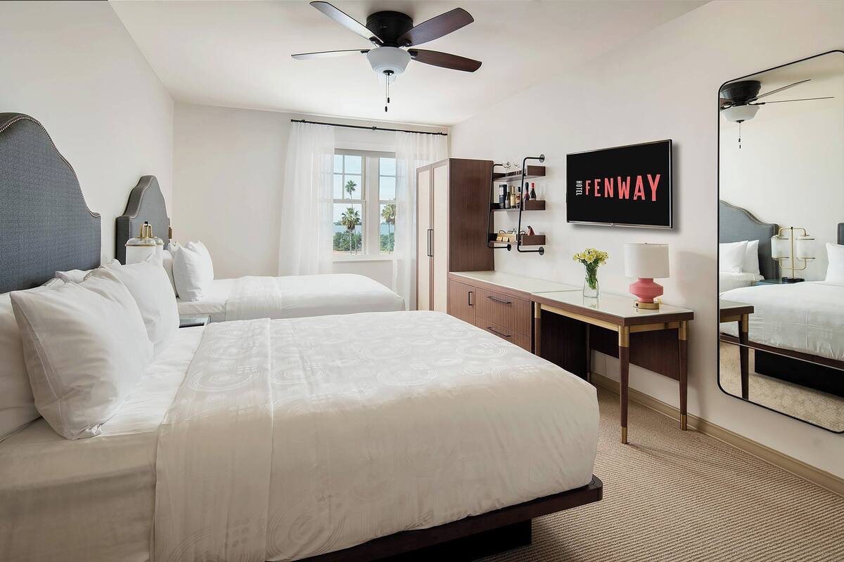 A hotel room with a large bed, a desk, a TV, and a wardrobe.