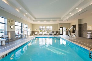 Una piscina interior con sillones de descanso y un cartel de socorrista.
