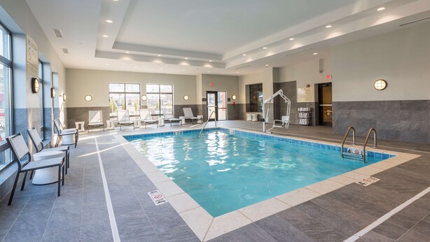 An indoor swimming pool with clear water, surrounded by lounge chairs and a tiled floor. - Hampton Inn & Suites West Lafayette (West Lafayette)