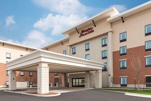 Un hotel Hampton Inn & Suites con entrada techada, fachada de ladrillo y numerosas ventanas.
