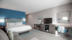Une chambre d’hôtel avec un lit, un bureau, une chaise, une télévision et une petite table.