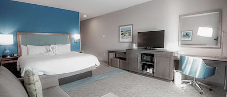 A hotel room with a bed, a desk, a chair, a television, and a small table.