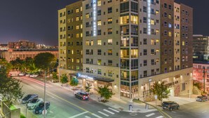 A multi-story hotel with a prominent 'Hyatt' sign, a covered entrance, and a parking lot with several cars. - Hyatt House Austin/Downtown (Austin)