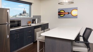 A modern kitchen with a view of a capitol building, a dining area with a white table, and a painting on the wall. - Hyatt House Austin/Downtown (Austin)