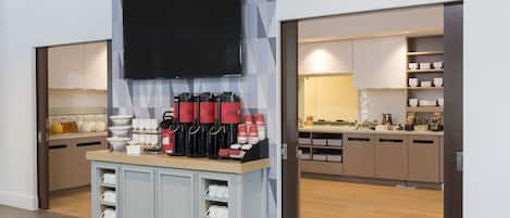 Una cocina moderna con televisor de pantalla plana sobre una estación de café, armarios de madera y salpicadero de azulejos.