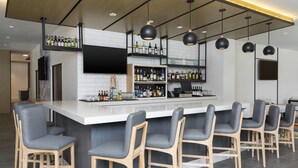 A modern bar area with a long counter, multiple bar stools, and a variety of bottles. - Hyatt House Austin/Downtown (Austin)