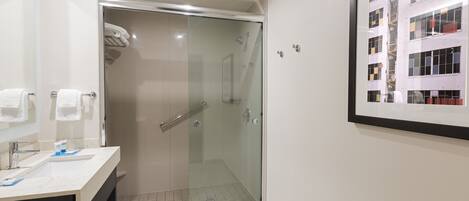 Une salle de bain moderne avec une douche à parois de verre, un lavabo doté d’un porte-serviettes et un tableau encadré au mur.
