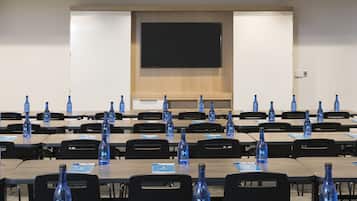 Un salón de conferencias con filas de mesas, cada una con una botella de agua azul con el rótulo 'HYATT'.