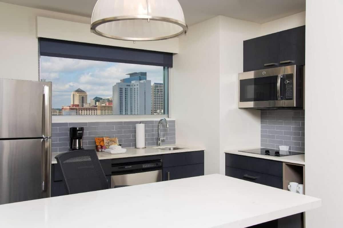 A modern kitchen with a stainless steel refrigerator, a built-in microwave, and a window with a city view.