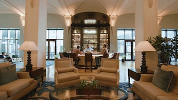 A spacious lobby with a bar area, comfortable seating, and large windows providing natural light.