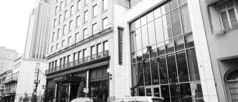 A hotel with a classic facade, large windows, and a visible address sign.
