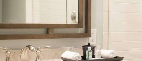 A bathroom with a large mirror, a sink with two faucets, and a towel rack.