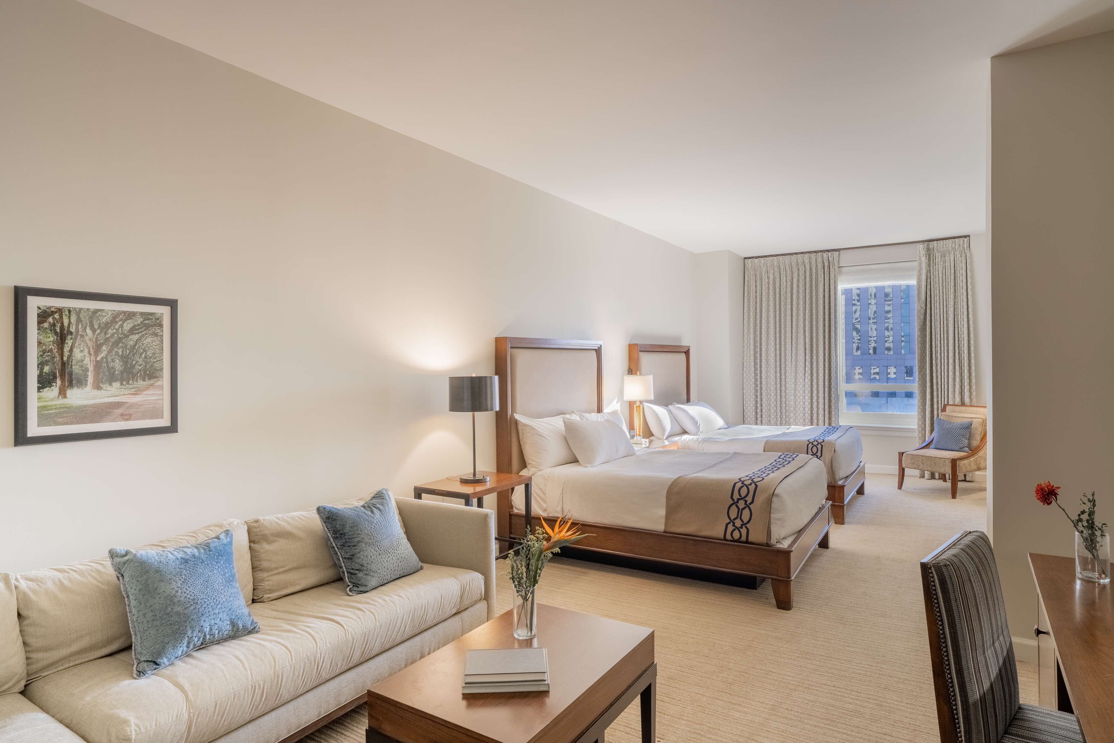 A hotel room with a bed, a sofa, a coffee table, and a chair.