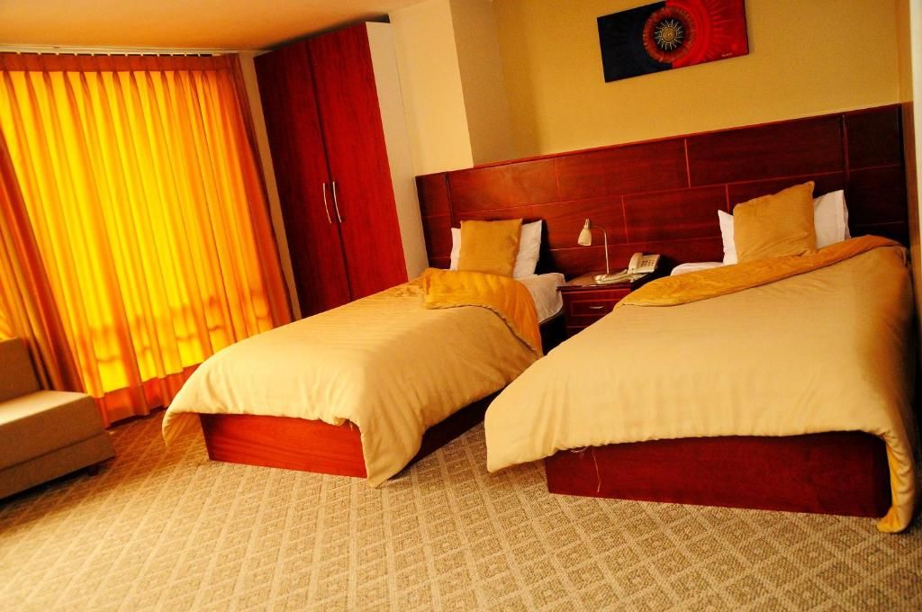 Une chambre d’hôtel avec deux lits, un bureau et une chaise.