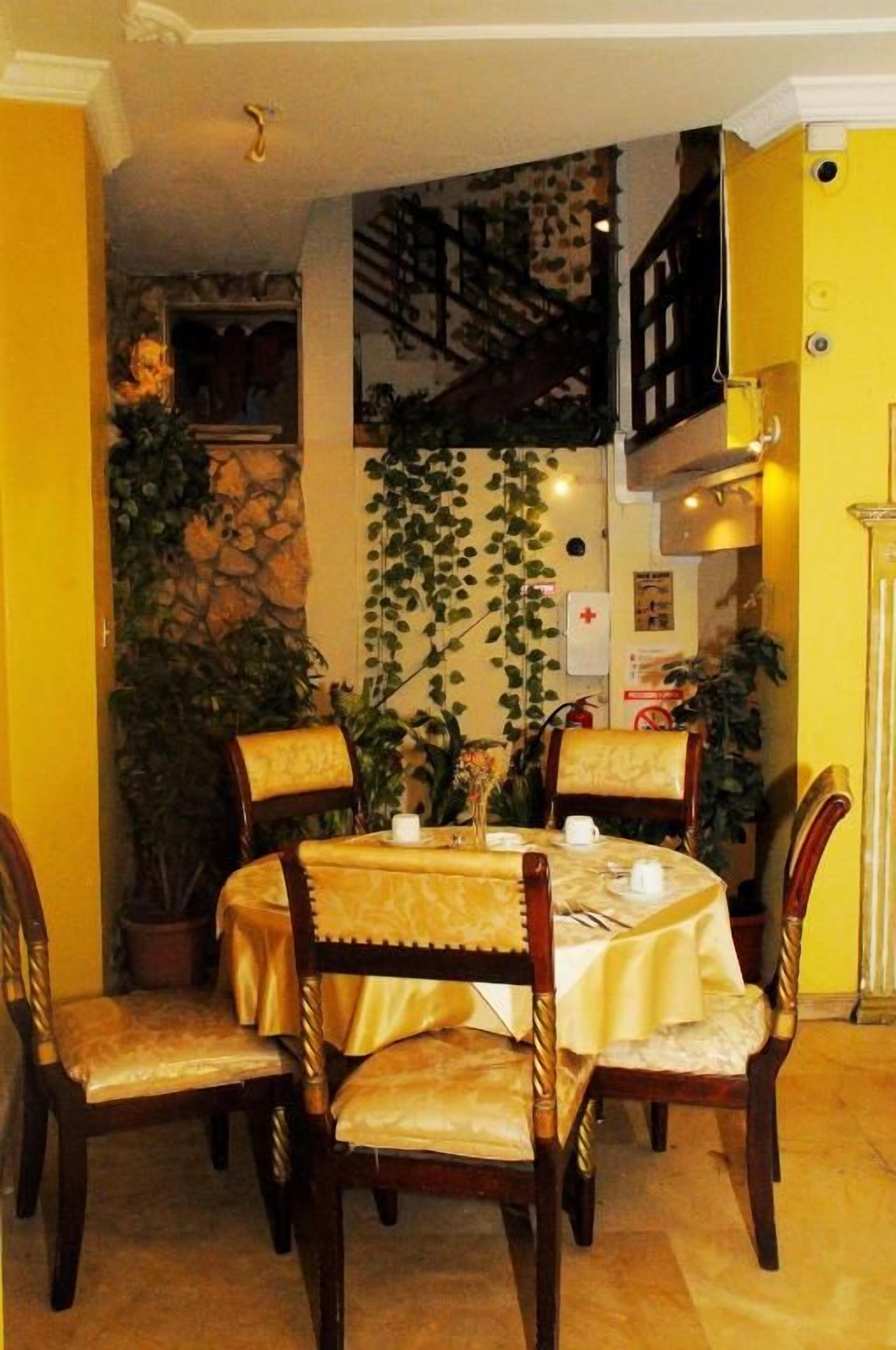 Un comedor con una mesa redonda, cuatro sillas y una pared amarilla.