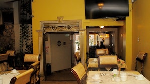 A dining area with tables set for service, a television mounted on the wall, and a door leading to another room.
