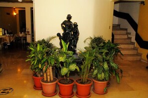 A statue in a lobby with potted plants around it. - Colony Inn Hotel (Ambato)