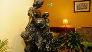 A statue of a woman holding a child in a lobby with a sofa and plants.