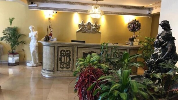 A reception area with a marble counter, a statue of a woman, and a statue of a man.