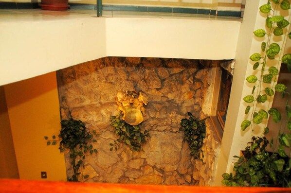 A stone fireplace with decorative elements and greenery. - Colony Inn Hotel (Ambato)