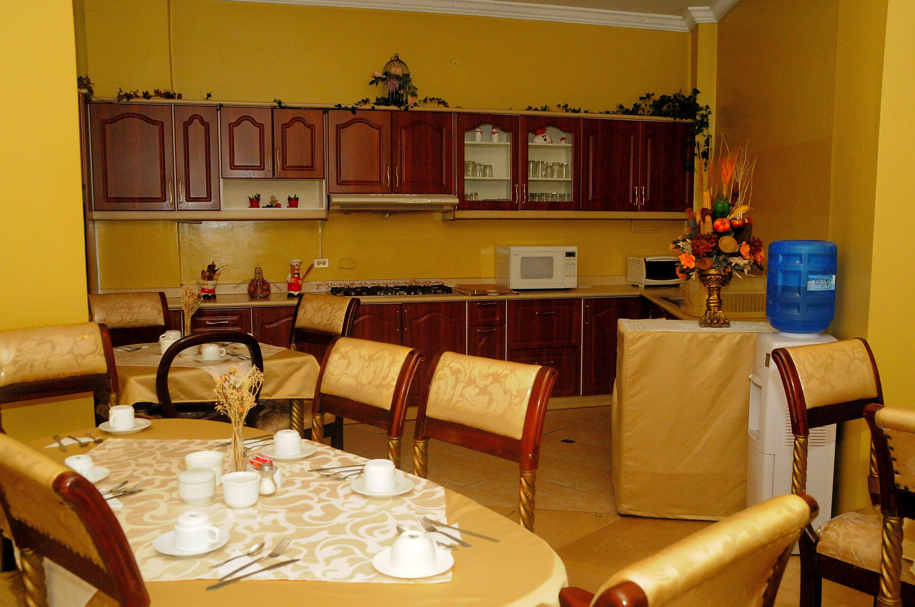 Un comedor con una mesa dispuesta para cuatro personas, microondas y armarios de madera al fondo.