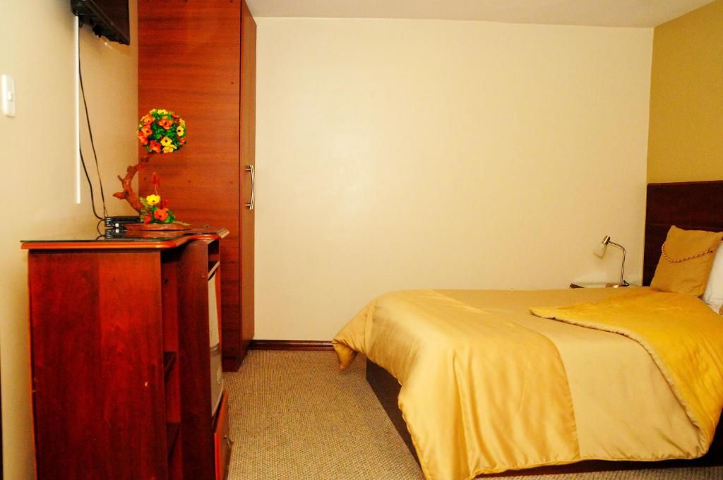 Ein Hotelzimmer mit einem Bett, einem Holztisch und einem an der Wand befestigten Fernseher.