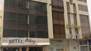 A hotel named 'Colony Hotel' with a large window facade and a signboard.