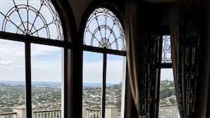 A room with two leather armchairs, a small table with magazines, and large windows with a view of a residential area. - Hackthorne Gardens Luxury Accommodation (Christchurch)