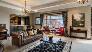 A spacious living room with a leather sofa, a coffee table, and a bar area with shelves of bottles. - Hackthorne Gardens Luxury Accommodation (Christchurch)
