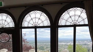 A room with two armchairs, a small table, and large windows with a view of a cityscape. - Hackthorne Gardens Luxury Accommodation (Christchurch)