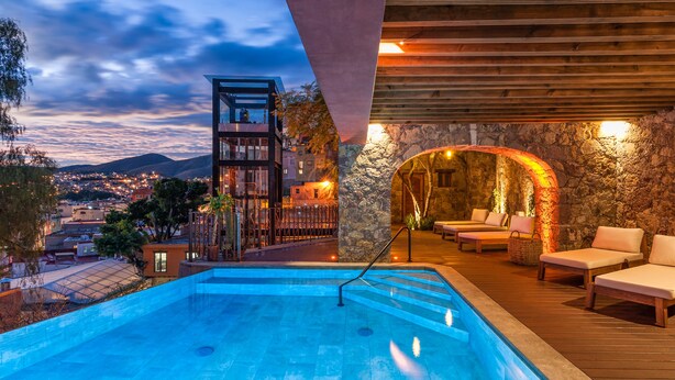 A rooftop pool with a view of the city, a lounge area with seating, and a stone wall structure. - Casa del Rector Hotel Boutique - Adults Only (Guanajuato)