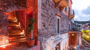 A stone building with a staircase leading to a balcony, potted plants, and a view of a town in the background. - Casa del Rector Hotel Boutique - Adults Only (Guanajuato)