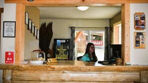 A reception desk at Kootenai Falls Inn with a wooden frame, framed pictures on the wall, a sign for the 8.4 rating, a glass display case with cookies, and a Rockstar Energy Drink cooler. - Country Inn (Libby)