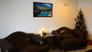 A living room with two leather sofas, a small table with a plant, a framed picture on the wall, and a Christmas tree. - Country Inn (Libby)