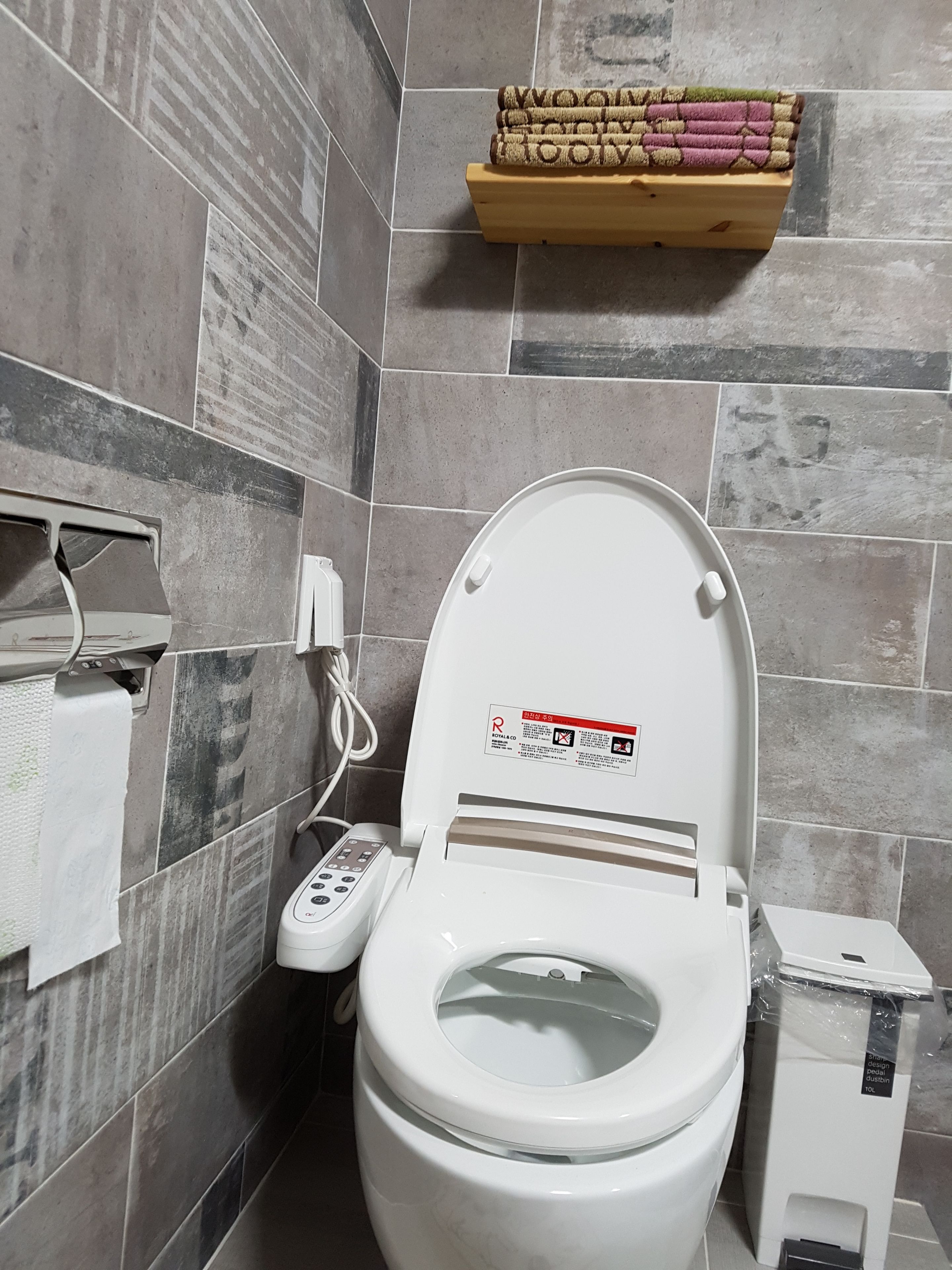 Un baño moderno con inodoro, secamanos y dispensador de papel higiénico.