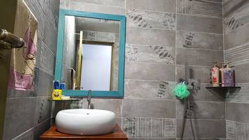 Un baño con un lavabo blanco, un mueble color esmeralda, un espejo con marco azul y paredes con azulejos.