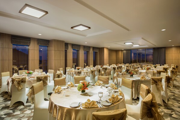 A banquet hall with round tables, chairs, and chandeliers. - Hotel Chanti (Semarang)