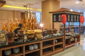 A buffet setup with various food items and serving ware. - Hotel Chanti (Semarang)