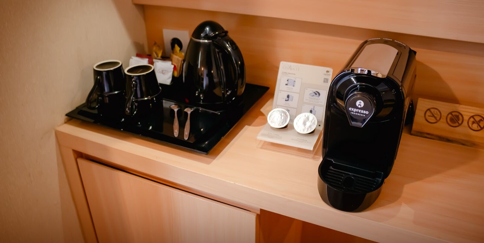 Una estación de café con cafetera, tazas y tetera sobre una encimera de madera.