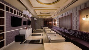 A modern restaurant with a long counter, cushioned seating, and decorative ceiling panels. - Hotel Chanti (Semarang)