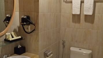 A bathroom with a sink, mirror, towel rack, toilet, and shower.