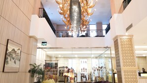 A spacious lobby with a high ceiling, a central chandelier, and a seating area with sofas and a coffee table. - Hotel Chanti (Semarang)