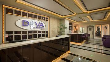 A modern hotel lobby with a reception desk, a bar area, and seating.