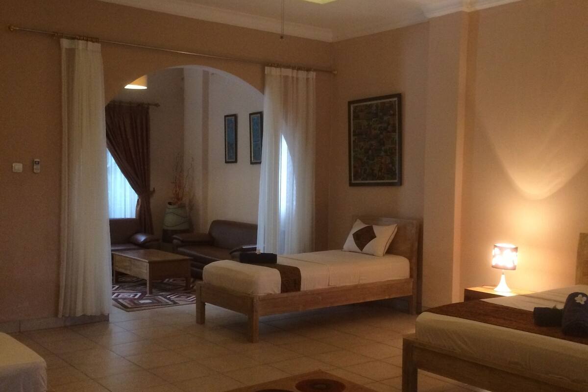 A hotel room with a bed, a sofa, a desk, and a ceiling fan.